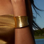 Profile view of a woman wearing the Gold Medium Basketweave Bracelet Cuff with a golden top, capturing the bracelet's protective qualities and its connection to meaningful spiritual practices.