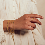 A hand adorned with the Gold Coils Black Snake Adjustable Ring among other jewelry pieces, embodying the essence of spiritual jewelry and zodiac significance, perfect for meaningful manifestation.