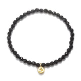 Om Black Onyx Gemstone Bracelet featuring faceted black onyx stones and a gold Om pendant, perfect for spiritual jewelry, meditation gifts, and yoga practices. This meaningful piece is a protective amulet embodying sacred and symbolic significance.