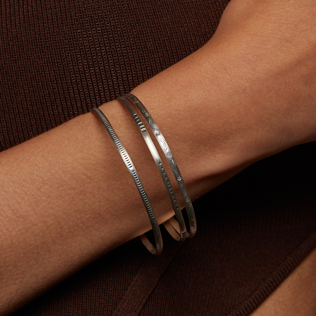 Close-up of a Silver Etched Bracelet Bangle titled Melody worn on a wrist, highlighting its elegant design, ideal for meaningful adornment in spiritual practices like yoga and meditation, serving as a protective amulet.