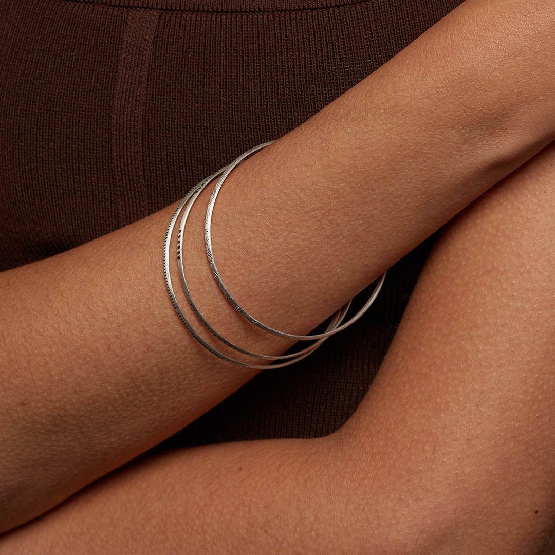 Showing multiple Silver Etched Bracelets Bangles titled Melody on a wrist, emphasizing their stylish appeal and symbolic meaning, making them great gifts for anyone interested in meditation, yoga, and spiritual jewelry.