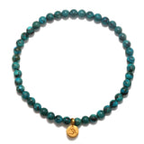 Protective Om Turquoise Gemstone Bracelet featuring turquoise beads and a gold Om symbol, perfect for spiritual jewelry and meditation, serving as a talisman for protection and manifestation. Ideal for yoga enthusiasts and those seeking meaningful accessories that connect with the sun and moon energies.