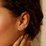 Stylish ear model showcasing the Abundant Blessings 14kt Gold Hamsa Earrings alongside other earrings, embodying spiritual meaning and charm with elements of protection and meditation.