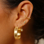 Close-up of Bold Spirit Gold Hoop Earrings paired with additional studs, representing a trendy ear styling. These earrings symbolize a bold spirit and are a perfect fit for anyone seeking spiritual jewelry that embodies protection and meaningful symbolism.