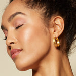 A model wearing Bold Spirit Gold Hoop Earrings, highlighting their elegant hoop design suitable for various styles. These earrings embody a bold spirit and serve as spiritual jewelry that resonates with meditation and meaningful connections.