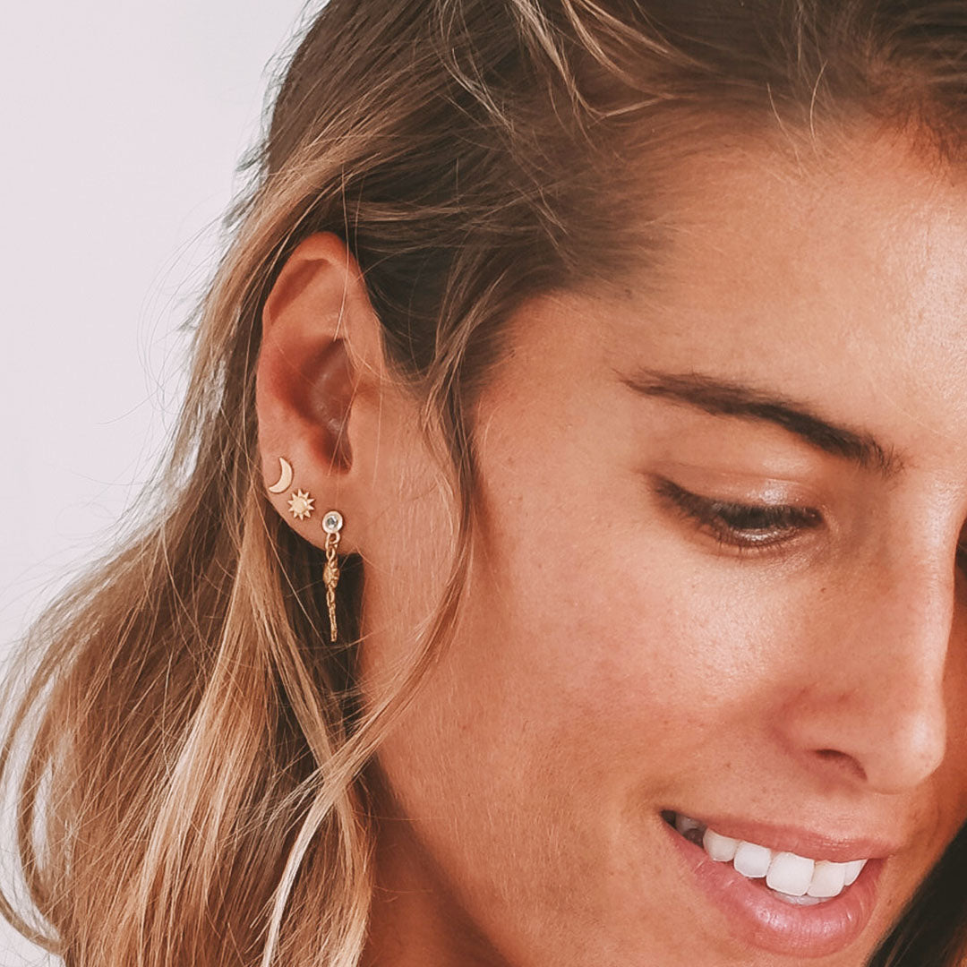 Portrait of a woman showcasing the Promise of Magic Earrings with a serene expression, highlighting the symbolism of the sun and moon in spiritual protection and yoga practices.