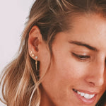 Portrait of a woman showcasing the Promise of Magic Earrings with a serene expression, highlighting the symbolism of the sun and moon in spiritual protection and yoga practices.