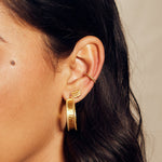 Side view of a model wearing Bold Spirit Gold Hoop Earrings alongside other jewelry, emphasizing their shining finish and spiritual significance. This jewelry piece is ideal for those who appreciate the meaningful aspects of spiritual jewelry and yoga.
