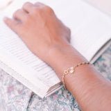 A close-up of a person wearing the Abundant Joy Tourmaline Gemstone Bracelet while reading a book. The bracelet, featuring tourmaline stones and a sun pendant, symbolizes vitality and leadership, making it a perfect piece of spiritual jewelry for meditation and manifestation.