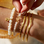 Close-up of the Gold Melody Bracelet Bangle alongside other bracelets, emphasizing its protective and sacred qualities in the context of mantra and spiritual jewelry.