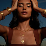 A striking image of a model wearing multiple layers of the Gold Mandala Necklace against a natural backdrop, blending the necklace's protective qualities with a serene vibe, suitable for mantra meditation and sacred practices.