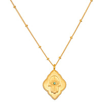 Cradled in Protection Gold Hamsa Necklace, an intricately designed spiritual jewelry piece symbolizing protection and blessings. This talisman features a hamsa hand with an evil eye and emerald gemstone, making it a meaningful charm for meditation and manifestation in your yoga practice. Perfect for those who resonate with zodiac energies, this necklace embodies the essence of sun and moon, enhancing your spiritual journey.