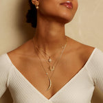 The Illuminated Path Gold Moon Necklace is elegantly displayed on a model, featuring a crescent moon and star, embodying themes of spirituality and meaningful charm. Ideal for those seeking protection, meditation, and deeper connections to their zodiac and spiritual practices.