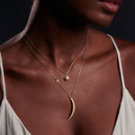 Close-up of the Illuminated Path Gold Moon Necklace on a woman's neckline, highlighting the beautiful crescent moon and star charms. This spiritual jewelry serves as a talisman for protection, making it a perfect addition for yoga and meditation enthusiasts.