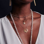 Model displaying the Incandescent Glow Gold Starburst Necklace in a layered look, emphasizing its role as a protective and spiritual charm for manifestation and connecting with the essence of the sun and moon in yoga.