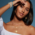 Model wearing the Emergence Gold Sunburst Necklace layered with other spiritual jewelry, emphasizing its significance as a meaningful talisman for manifestation and protection, ideal for yogis and those seeking spiritual connection.
