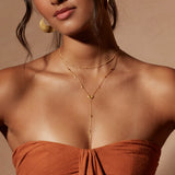 Model wearing the Light of Day Gold Lariat Necklace, showcasing its elegant design that embodies protection and charm, ideal for yoga enthusiasts and spiritual seekers.