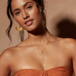 Close-up of the Light of Day Gold Lariat Necklace on a model, highlighting its radiant citrine stone and intricate details, embodying the essence of spiritual, protective jewelry linked to the sun and yoga practices.