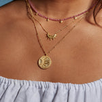 Model wearing the First Light Gold Medallion Reversible Pendant Necklace layered with other pieces, capturing the essence of spiritual jewelry and charm that reflects the harmony of sun and moon energies, perfect for yoga and personal protection.