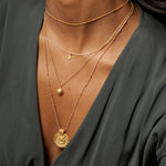 Model showcasing the Here Comes the Sun Necklace layered with other delicate gold chains, representing the sun's vitality as part of a spiritual jewelry collection. This combination highlights elements of meditation, protection, and meaningful adornments for those who align with the sun's powerful manifestation energy.