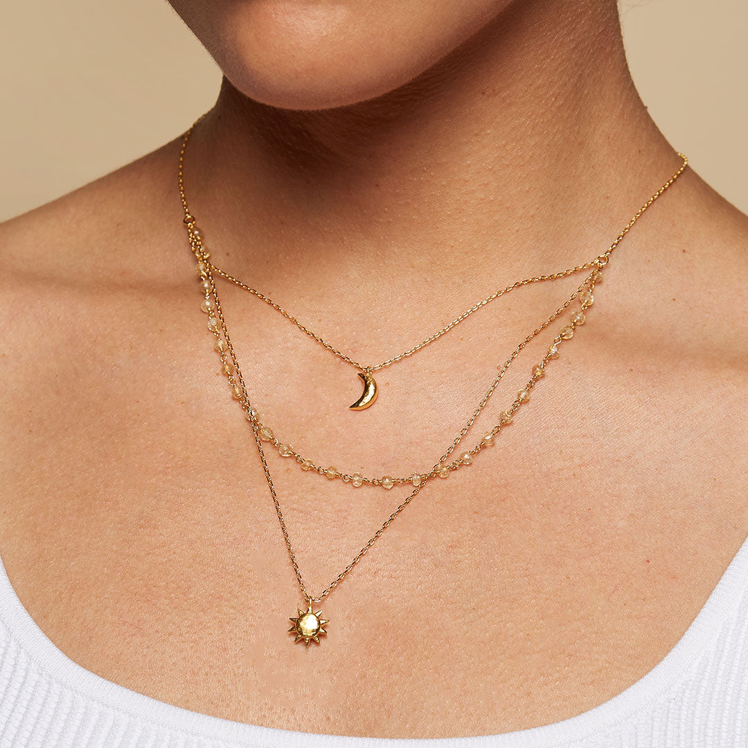 Close-up of the Cast a Light, Sun, Moon & Citrine Triple Necklace worn elegantly. This spiritual jewelry piece combines the sun and moon motifs, embodying meaning and vitality. A great talisman for those interested in zodiac and mindfulness during meditation.