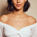 A model wearing the Gold Mandala Necklace with a stylish off-shoulder top, highlighting its symbolic nature, ideal as a meaningful amulet for manifestation and protection, perfect for a modern spiritual lifestyle.