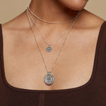 Elegant display of the Journey Forward Lotus Silver Necklace layered with other necklaces, representing a chic choice for spiritual jewelry. This necklace serves as a charm for those seeking meaningful connections to yoga and the zodiac.