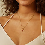 Model wearing the Emerald Bezel Charm on a delicate gold necklace, showcasing spiritual jewelry that symbolizes zodiac meanings and serves as a talisman of intention for yoga and meditation practices.
