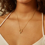 A model wearing the Peridot Bezel Charm on a delicate gold necklace, embodying a connection to zodiac energy and spiritual protection during yoga and meditation practices.