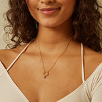 A model wearing the Garnet Bezel Charm necklace, showcasing its elegance in 18kt gold plate. This spiritual jewelry piece serves as a meaningful talisman for love, friendship, and guidance, perfect for meditation and manifestation practices. Ideal for those drawn to the symbolism of zodiac and spiritual connections.