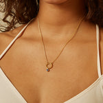 Model wearing a Sapphire Bezel Charm on a delicate gold necklace, showcasing the charm’s vibrant sapphire and elegant design. This meaningful spiritual jewelry piece embodies qualities of protection and love, making it a perfect talisman for zodiac placements and a wonderful addition to any meditation or yoga practice.