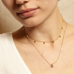 Model showcasing the delicate Moon Phases of Femininity Gold Choker paired thoughtfully with other necklaces. This sacred piece of jewelry is perfect for manifesting intentions and encompasses spiritual themes of protection, significance, and the phases of life.