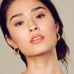 A model wearing Interwoven Gold Hoop Earrings, highlighting their beauty and spiritual essence. These earrings serve as a talisman for manifestation, resonating with sun and moon energies, making them ideal for yoga and meditation.
