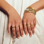 A collection of elegant hands adorned with various rings including the Shielded from Negativity Eye Gold Adjustable Ring, representing individuality and spirituality. This assortment reflects the essence of meditation gifts and meaningful symbolic jewelry, perfect for manifestation and yoga enthusiasts.