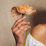 A hand holding a dried flower while showcasing the Gold Coils Black Snake Adjustable Ring, embodying spirituality and protection as a talisman, ideal for yoga and meditation practices.