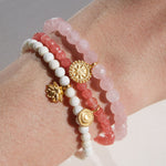 Awaken Love Mandala Rose Quartz Gemstone Bracelet displayed in a stack with other spiritual jewelry, showcasing the delicate golden mandala charm, symbolizing love, compassion, and the connection to the sacred infinite cycle. This meaningful bracelet is perfect for meditation and manifestation practices.