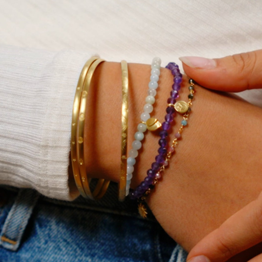 A collection of bracelets including the Abundant Joy Tourmaline Gemstone Bracelet, showcasing layered styles with gold accents and colorful stones, perfect for spiritual and meaningful adornment during meditation, yoga, and as a talisman for zodiac protection.
