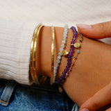 A collection of bracelets including the Abundant Joy Tourmaline Gemstone Bracelet, showcasing layered styles with gold accents and colorful stones, perfect for spiritual and meaningful adornment during meditation, yoga, and as a talisman for zodiac protection.