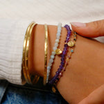 A stylish display of the Tranquility Lotus Amethyst Gemstone Bracelet among other bracelets on a wrist, representing spiritual jewelry that embodies peace and new beginnings, perfect as meditation gifts or symbolic items for manifestation, sacred protection, and yoga practice.