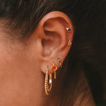 A close-up of a person wearing Interwoven Gold Hoop Earrings, showcasing elegance and spiritual significance. This jewelry piece is perfect for meditation and aligns with zodiac energies, representing protection and meaningful connections.