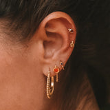 A close-up of a person wearing Interwoven Gold Hoop Earrings, showcasing elegance and spiritual significance. This jewelry piece is perfect for meditation and aligns with zodiac energies, representing protection and meaningful connections.